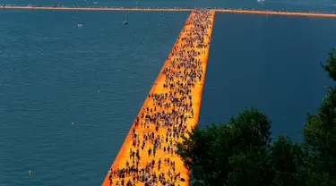 Ribuan orang berjalan di atas sebuah instalasi "The Floating Piers" yang merupakan karya seniman Bulgaria, Christo Vladimirov Javacheff di Danau Iseo, Italia, (24/6). Karya menakjubkan ini diharapkan dapat menarik wisatawan. (REUTERS/Stefano Rellandini)