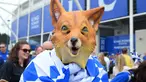 Seorang fans Leicester City mengenakan topeng maskot kebanggan Leicester City saat merayakan titel juara Liga Inggris 2015-2016 di Areal Stadion King Power (7/5/2016). (AFP/Glyn Kirk)