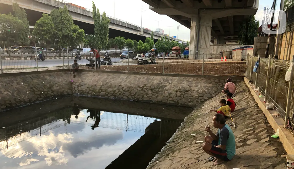 Sejumlah warga memancing ikan di kubangan yang berada di Jalan DI Panjaitan, Jatinegara, Jakarta, Selasa (16/6/2020). Meski telah dipagari, sejumlah warga tetap memancing ikan di lokasi yang merupakan saluran pembuangan tersebut. (Liputan6.com/Immanuel Antonius)