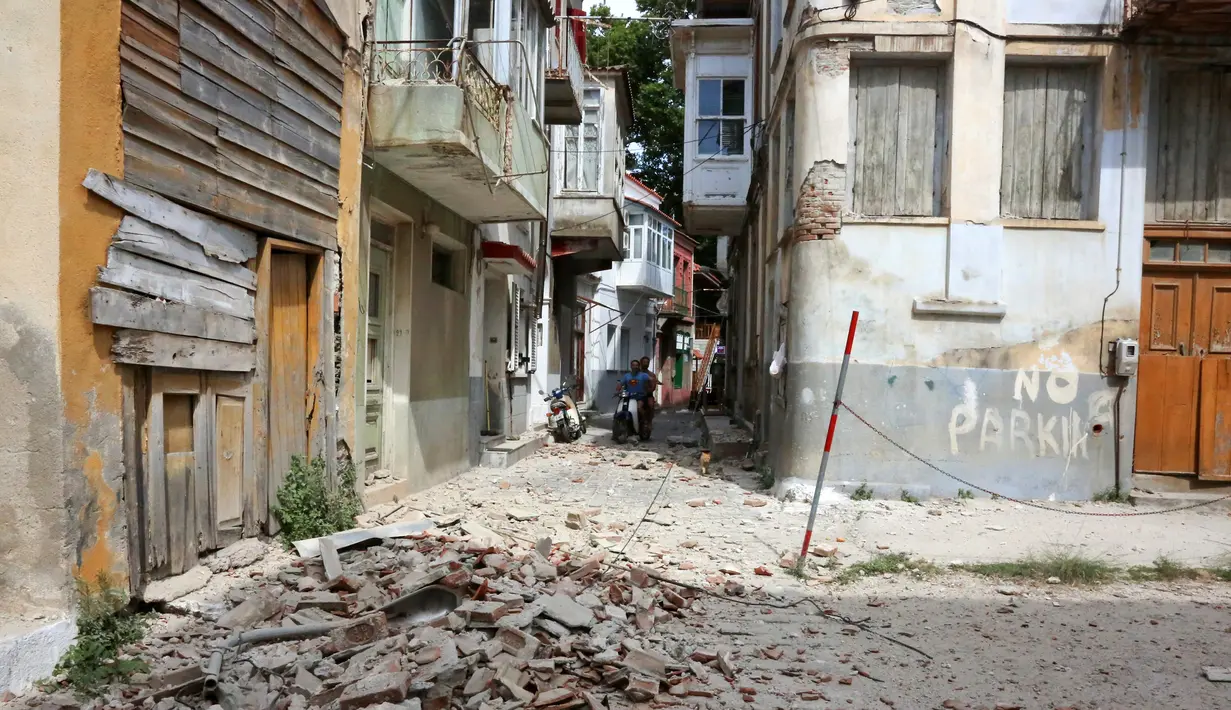Warga mengamati puing bangunan yang hancur setelah gempa bumi di pulau Lesbos, Yunani Timur, Senin (12/6). Gempa 6,3 SR itu mengakibatkan kerusakan pada beberapa rumah dan sejumlah bangunan di pulau Lesbos. (Manolis Lagoutaris/InTime News via AP)