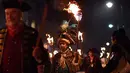 Peserta melakukan pawai melintasi jalan dalam perayaan Bonfire Night di Sussex Timur, Inggris, Selasa (5/11/2019). Setiap tahunnya pada tanggal 5 November, warga Inggris menggunakan kostum, berdandan, berkumpul, lalu melakukan pawai ke seluruh penjuru kota sambil membawa obor. (Ben STANSALL/AFP)