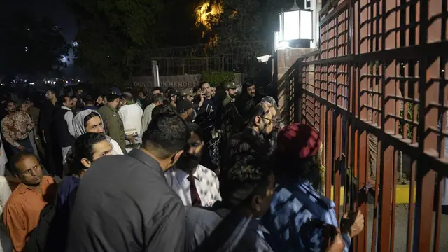 Anggota media dan polisi berkumpul di pintu masuk utama rumah sakit tempat mantan PM Pakistan Imran Khan dirawat, di Lahore, Pakistan, Kamis, 3 November 2022. (Saleem Ahmed/AP Photo)