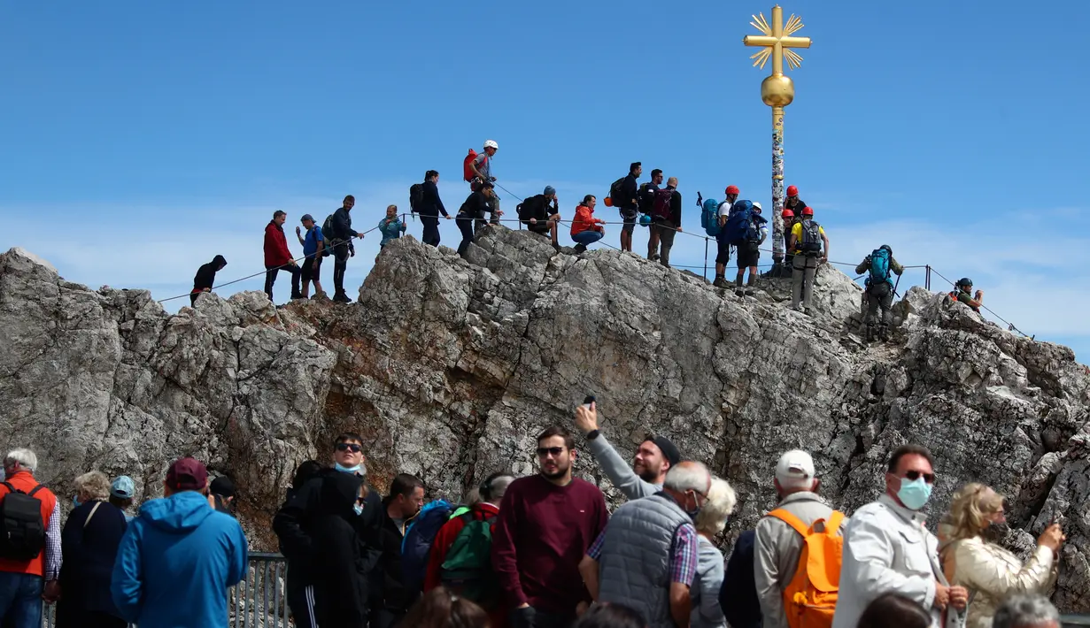 Orang-orang mengantre untuk mencapai puncak salib di puncak gunung tertinggi Jerman, Zugspitze, dekat Garmisch-Partenkirchen, Jerman pada 19 Agustus 2020. Setiap tahunnya gunung dengan ketinggian 2.962 meter tersebut membuat sekitar setengah juta pengunjung terpesona. (AP Photo/Matthias Schrader)