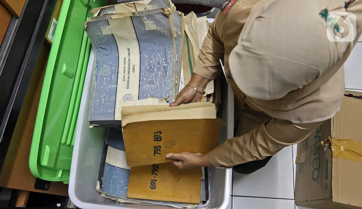 Petugas dari sekolah sedang memeriksa arsip di SMAN 77, Cempaka Putih, Jakarta Pusat, Rabu (24/11/2021). Digitalisasi arsip untuk meningkatkan kesadaran pentingnya menata dan menyelamatkan arsip penting. (Liputan6.com/Herman Zakharia)
