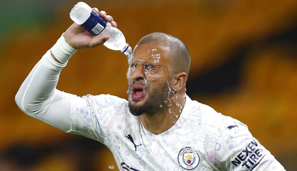 Bek Manchester City, Kyle Walker, membasahi wajahnya dengan air saat melawan Wolverhampton Wanderers pada laga Liga Inggris di Stadion Molineux, Senin (21/9/2020). Manchester City menang dengan skor 3-1. (Marc Atkins/Pool via AP)