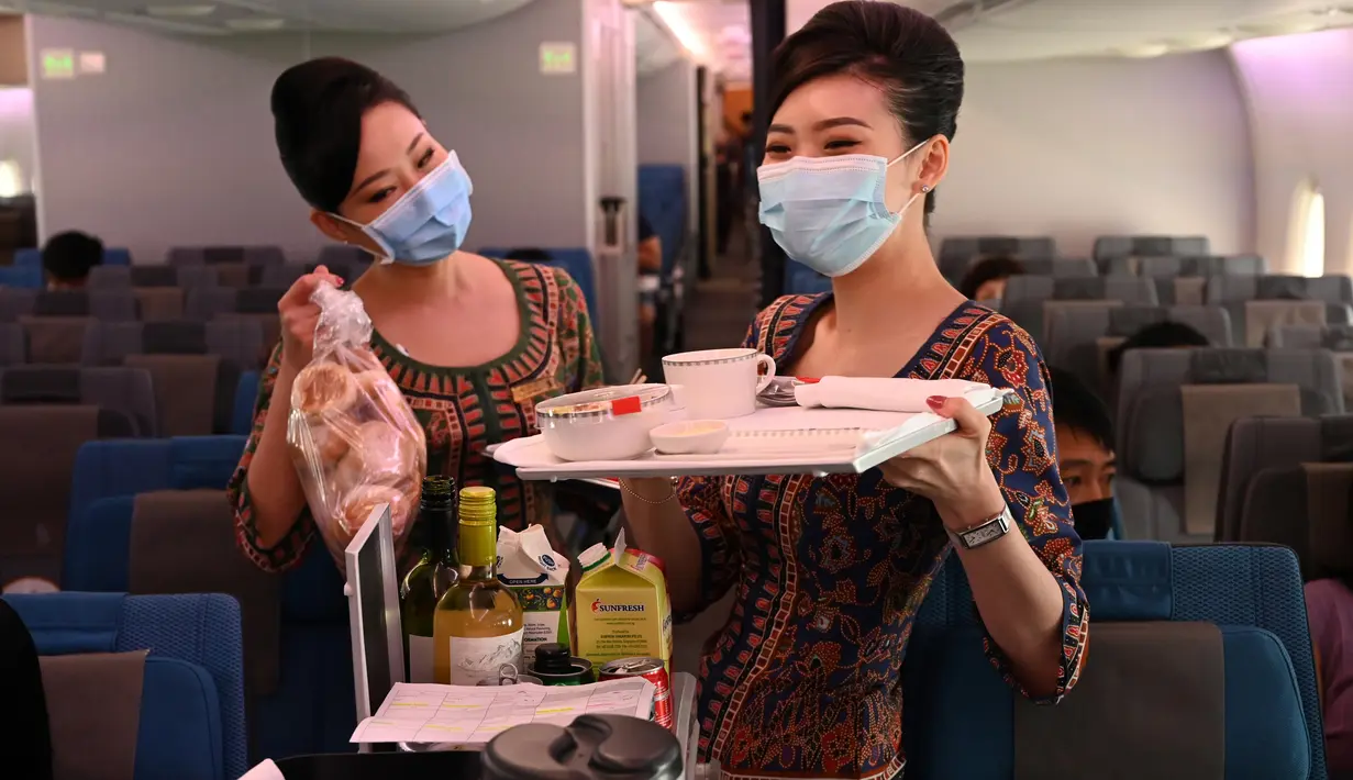 Pramugari Singapore Airlines menyiapkan menu untuk kelas ekonomi saat makan siang perdana di Restaurant A380 @Changi di pesawat Airbus A380, di Bandara Internasional Changi, 24 Oktober 2020. Terdapat dua pilihan kelas lainnya selain ekonomi dan suites yakni Ekonomi premium. (ROSLAN RAHMAN/AFP)