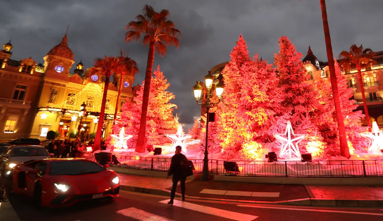 Orang-orang melintas dekat tampilan lampu dan dekorasi menyambut Natal yang dipajang di depan Kasino Monte-Carlo di Monako pada 7 Desember 2018. (Photo by VALERY HACHE / AFP)