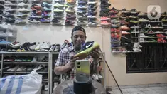 Bajuri (45) saat memasarkan sepatu impor bekas melalui media sosial di toko Second BJR, Kali Baru Timur, Cilincing, Jakarta Utara, Rabu (1/6/2022). Bursa sepatu impor bekas bermerek dalam beberapa tahun terakhir mulai ramai diminati warga lantaran harga yang terjangkau dan kualitas bahan. (merdeka.com/Iqbal S. Nugroho)