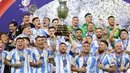 Pemain Argentina, Lionel Messi mengangkat trofi saat merayakan juara pada laga final Copa America 2024 di Hard Rock Stadium, Miami, Florida, Senin (15/07/2024) WIB. (AFP/Charly Triballeau)