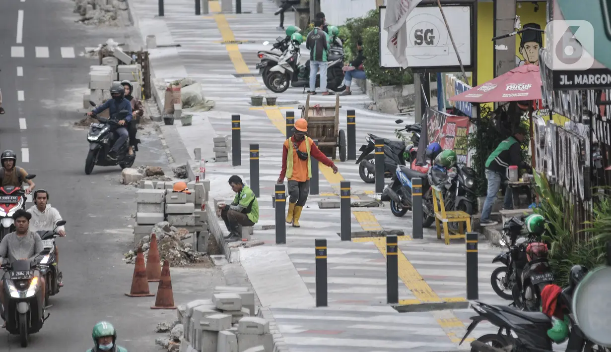 Aktivitas pekerja saat menyelesaikan proyek revitalisasi trotoar di Jalan Margonda Raya, Depok, Jawa Barat, Minggu (4/12/2022). Penataan trotoar di Jalan Raya Margonda, Depok, mengusung konsep instagramable. Konsep tersebut sebagai upaya meningkatkan minat masyarakat untuk berjalan kaki.(merdeka.com/Iqbal S Nugroho)