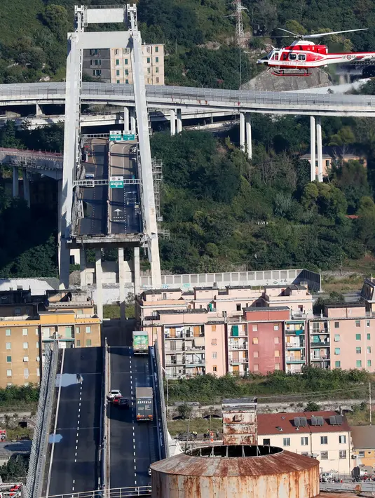Sejumlah kendaraan berada di atas jembatan Morandi, dekat dengan bagian jalan layang yang runtuh, di kota Genoa, italia, Selasa (14/8). Jembatan yang dibangun pada 1960-an itu ambruk saat hujan deras dan angin kencang. (AP/Antonio Calanni)