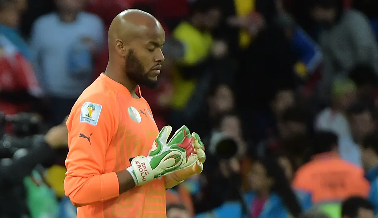 Kiper Aljazair, Rais Mbohli tertangkap kamera tengah mengambil kurma di sisi gawangnya saat penghujung babak pertama dimana telah tiba waktu berbuka puasa. Hasil akhir, Aljazair kalah 1-2 lewat babak perpanjangan waktu. (AFP/Gabriel Bouys)