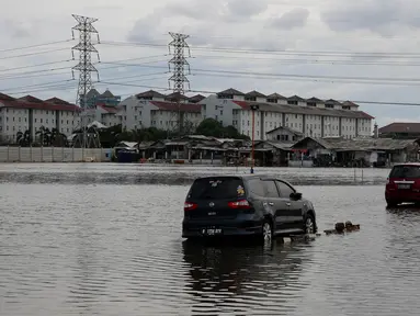 Dua mobil berada di genangan air akibat banjir rob di kawasan Muara Angke, Jakarta, Kamis (4/1). Banjir rob yang merendam kawasan Muara Angke itu disebabkan oleh fenomena Supermoon. (Liputan6.com/JohanTallo)