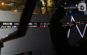 Pengunjung melintas dilayar pergerakan saham di BEI, Jakarta, Senin (30/12/2019). Pada penutupan IHSG 2019 ditutup melemah cukup signifikan 29,78 (0,47%) ke posisi 6.194.50. (Liputan6.com/Angga Yuniar)