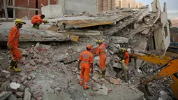 Tim penyelamat mencari korban yang terjebak reruntuhan gedung ambruk di desa Shahberi, pinggiran New Delhi, India, Rabu (18/7). Menurut polisi, bangunan yang selesai dibangun beberapa tahun lalu itu belum memiliki banyak penghuni. (AP Photo/Altaf Qadri)
