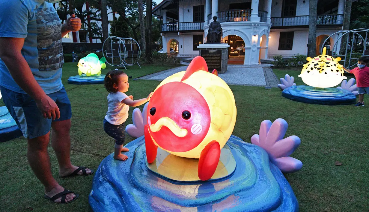 Seorang anak menyentuh instalasi lentera menjelang perayaan Festival Pertengahan Musim Gugur di Singapura (14/9/2020). (Xinhua/Then Chih Wey)