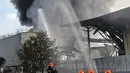 Petugas pemadam kebakaran berupaya memadamkan api yang melahap sebuah pabrik pengolahan limbah di Singapura, Kamis (23/2). Tidak ada korban jiwa akibat kebakaran di tempat pengolahan limbah kimia dan bahan yang mudah terbakar tersebut. (Roslan RAHMAN/AFP)