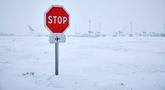 Foto ini menunjukkan rambu berhenti di dekat landasan pacu saat salju menyelimuti landasan, menyebabkan pembatalan penerbangan di Bandara Orly, selatan Paris pada 7 Januari 2026. Cuaca dingin ekstrem dan hujan salju lebat yang melanda sebagian besar wilayah Eropa, menyebabkan gangguan perjalanan yang meluas serta merenggut nyawa enam orang dalam serangkaian insiden terkait cuaca buruk di benua tersebut. (Kiran RIDLEY/AFP)
