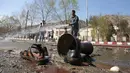 Petugas pemadam kebakaran membersihkan lokasi pemboman bunuh diri di dekat Universitas Kabul, Afghanistan, (21/3). Pembom bunuh diri itu menyerang di jalan menuju kuil Syiah di ibukota Afghanistan. (AP Photo/Rahmat Gul)