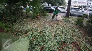 Pekerja membersihkan sampah berserakan di taman yang rusak di depan gedung Balai Kota Jakarta, Jumat (14/10). Taman tersebut rusak akibat banyaknya pengunjuk rasa yang menginjak-injak serta duduk di atas tanaman. (Liputan6.com/Immanuel Antonius)