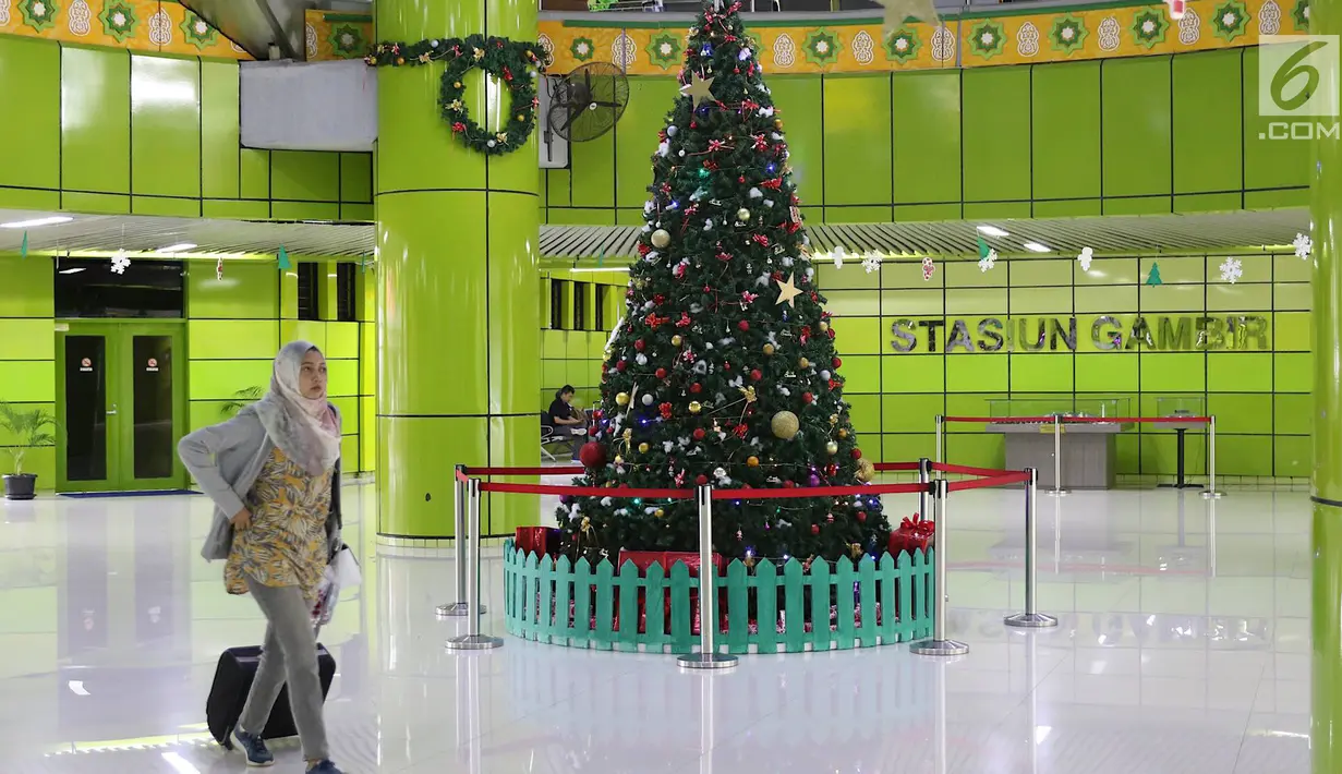 Penumpang melintas di dekat dekorasi pohon Natal di Stasiun Gambir, Jakarta, Jumat (21/12). Dekorasi tersebut dibuat untuk memercantik suasana Stasiun Gambir dalam rangka menyambut Hari Natal dan Tahun Baru 2019. (Liputan6.com/Immanuel Antonius)