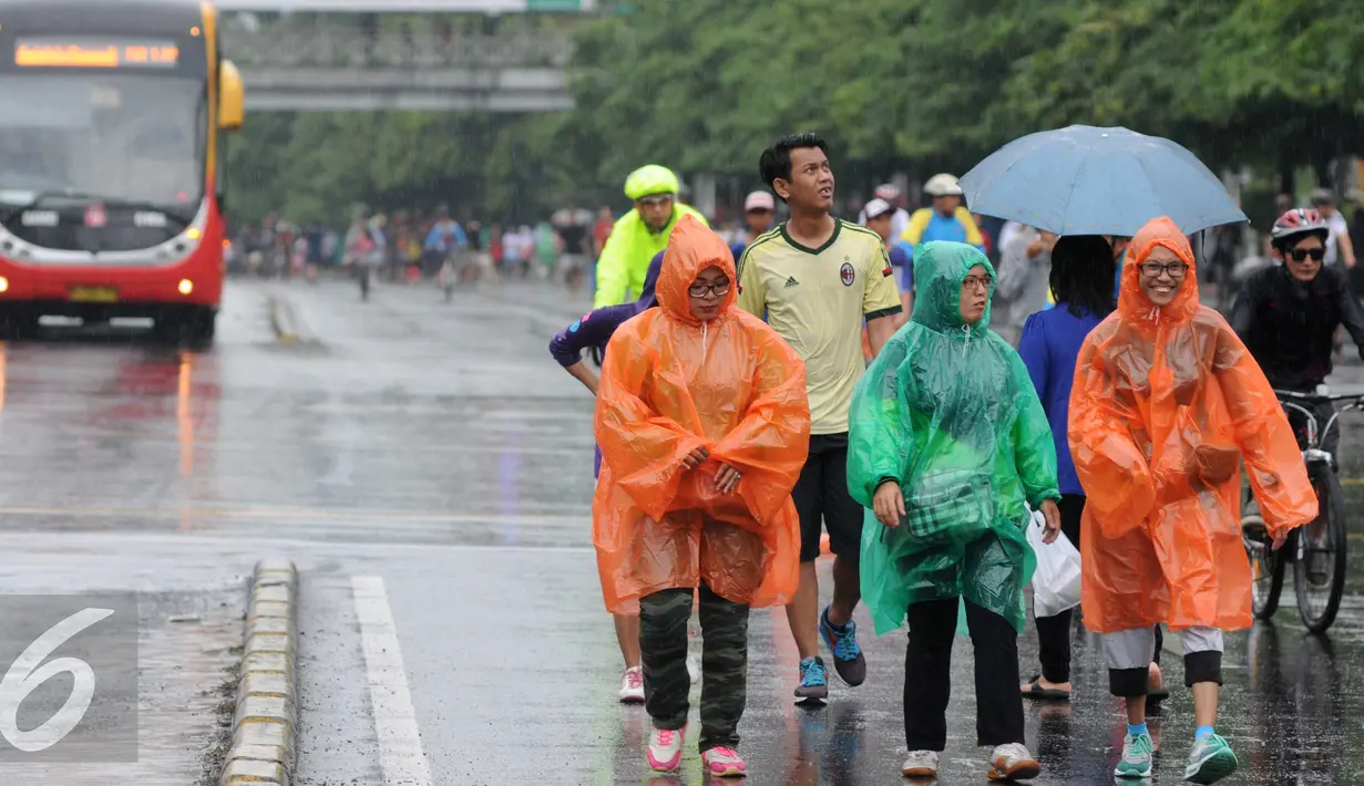 Sejumlah warga mengenakan jas hujan saat mengikuti kegiatan Car Free Day, Jakarta, Minggu (24/1/2016). Meski hujan mengguyur Ibu Kota sejak semalam, kegiatan CFD pagi di kawasan Bundaran Hotel Indonesia masih tetap ramai. (Liputan6.com/Helmi Affandi)