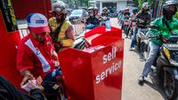 Seorang pekerja SPBU (kiri) menerima pembayaran dari pengendara yang mengantre untuk mengisi bahan bakar sepeda motor mereka di sebuah Stasiun Pengisian Bahan Bakar Umum (SPBU), Jakarta pada Rabu 1 April 2026. Pemerintah resmi tidak mengubah harga Bahan Bakar Minyak (BBM) di dalam negeri, baik harga BBM subsidi maupun non subsidi. (BAY ISMOYO/AFP)