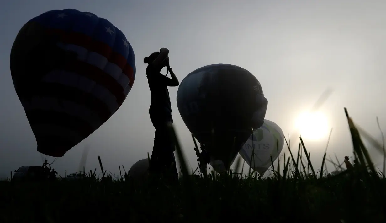 Peserta dari Bedminster, Zan Davies mengambil foto balon pada hari pertama Festival QuickChek New Jersey di Kota Readington, New Jersey (28/7). Festival balon udara panas ini merupakan acara yang ke-35 kalinya. (AP Photo/Julio Cortez)