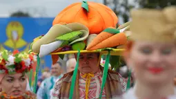 Seorang warga Belarusia memakai baju adat dan topi berhiaskan sayuran saat mengikuti Festival Dozynki di Minsk, Belarusia, Minggu (7/10). Festival ini merupakan bentuk syukur setelah hasil panen yang melimpah. (AP Photo/Sergei Grits)