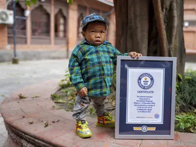 Dor Bahadur Khapangi memegang sertifikat Guinness World Record di Kathmandu, Nepal, Selasa (24/5/2022). Khapangi yang lahir pada 14 November 2004 memegang rekor sebagai remaja terpendek di dunia. (AP Photo/Niranjan Shrestha)