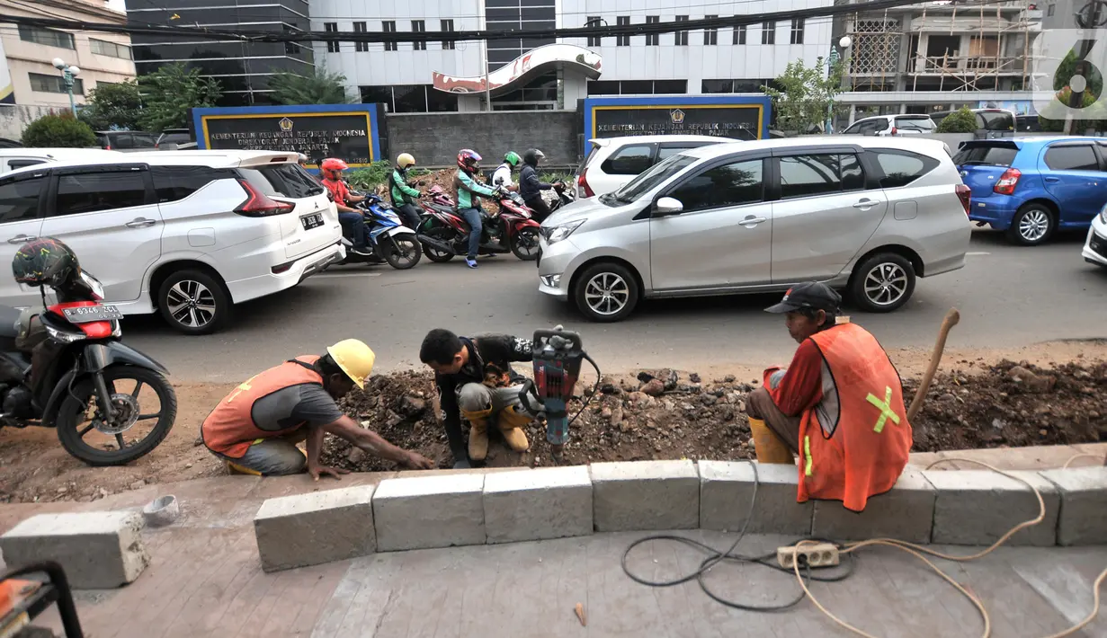 Aktivitas pekerja saat menyelesaikan proyek revitalisasi trotoar di Jalan Tebet Raya, Jakarta, Selasa (5/11/2019). Adanya proyek revitalisasi trotoar di sepanjang Jalan Tebet Raya mengakibatkan kemacetan di kawasan tersebut semakin parah, terlebih saat jam sibuk. (merdeka.com/Iqbal Nugroho)