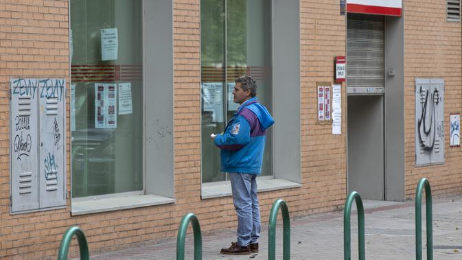 Seorang pria melihat pemberitahuan pada jendela kantor di Madrid, Spanyol, Selasa (28/4/2020). Pandemi virus corona COVID-19 mengakibatkan tingkat pengangguran Spanyol naik menjadi 14,4 persen pada kuartal pertama 2020. (AP Photo/Paul White)