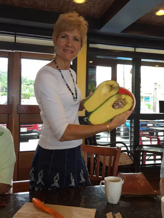 Seorang wanita Hawaii, Pamela Wang berpose dengan buah alpukat super jumbo di Kealakekua, 28 November 2017. Pamela Wang tak sengaja menemukan buah alpukat ini di pinggir jalan saat ia ingin mengambil koran miliknya. (facebook.com/pamela.b.wang)