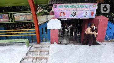 Sejumlah siswa berjalan keluar melintasi jalan darurat yang dibuat pihak sekolah di SDN Pondok Cina 1, Depok, Jawa Barat, Rabu (9/11/2022). Pembangunan trotoar Jalan Margonda Raya yang tidak membuat jalan darurat untuk siswa tersebut menghalangi pintu masuk SDN Pondok Cina 1 serta membahayakan siswa. (Liputan6.com/Herman Zakharia)