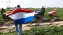 Penonton memegang bendera Belanda saat ajang balap sepeda Paris Roubaix 2023 yang menempuh Compiegne hingga Roubaix, Prancis utara, 9 April 2023. (AFP/Anne-Christine Poujoulat)