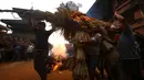 Umat Hindu Nepal membawa jerami untuk dibakar dalam perayaan Ghanta Karna di Bhaktapur di pinggiran Kathmandu, Nepal (21/7). Ritual ini untuk merayakan kekalahan iblis dalam mitos Ghanta Karna. (AFP Photo/Gopen Rai)