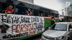 Suporter Persija berada di dalam bus melewati jalan Gatot Subroto menuju stadion Gelora Bung Karno, Jakarta, Minggu (9/12). Antusiasme ribuan suporter Persija bersiap mendukung tim kesayangannya bertanding melawan Mitra Kukar. (Liputan6.com/Faizal Fanani)