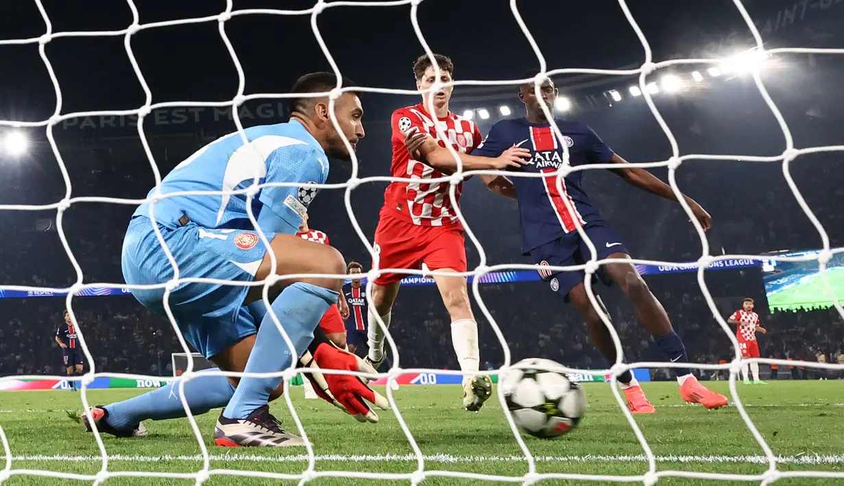 Kiper Girona, Paulo Gazzaniga (kiri) berusaha menangkap bola umpan silang dari PSG, Nuno Mendes pada laga Liga Champions 2024/2025 yang berlangsung di Parc des Princes, Paris, Prancis, Kamis (19/09/2024). (AFP/Franck Fife)