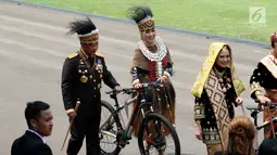 Kapolri Jendral Tito Karnavian bersama istri Tri Suswati mengenakan pakaian adat Papua membawa hadiah sepeda dari Presiden Jokowi usai peringatan HUT RI ke 72 di Istana Merdeka, Jakarta, Kamis (17/8). (Liputan6.com/Pool)
