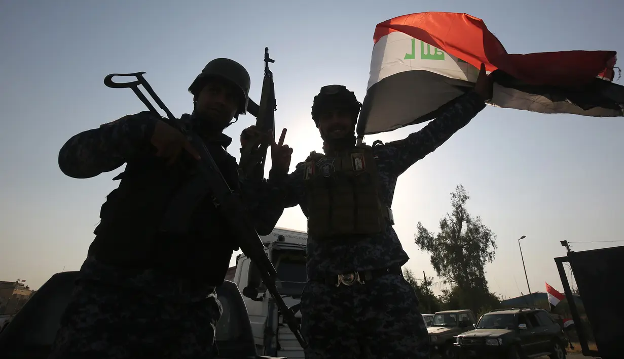 Anggota polisi Federal mengibarkan bendera nasional Irak saat merayakan keberhasilan mereka menyingkirkan militan ISIS dari Kota Tua Mosul, Minggu (9/7). ISIS merebut Mosul pada musim panas 2014. (AHMAD AL-RUBAYE/AFP)