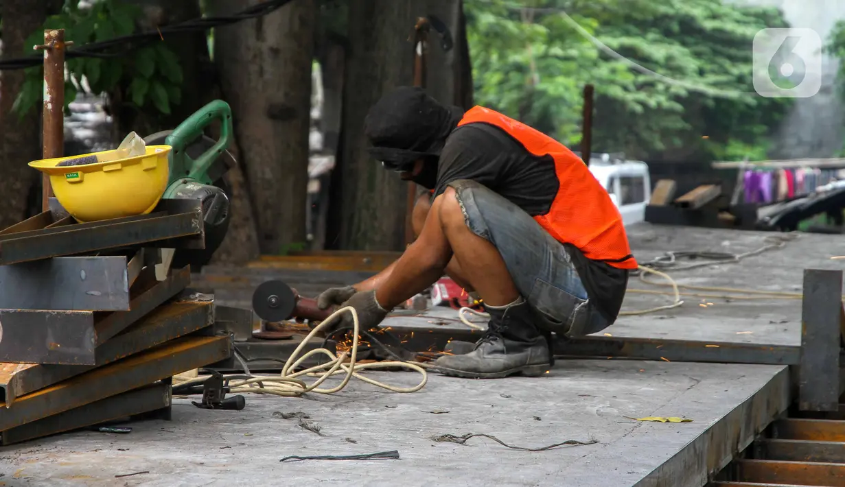 Pekerja menyelesaikan proyek pembangunan jembatan penghubung antarkampung di kawasan Pondok Pinang, Jakarta, Jumat (13/12/2019).  Jembatan yang menghubungkan permukiman di daerah Pondok Pinang dengan kawasan Bintaro tersebut ditargetkan rampung pada akhir Desember. (Liputan6.com/Faizal Fanani)