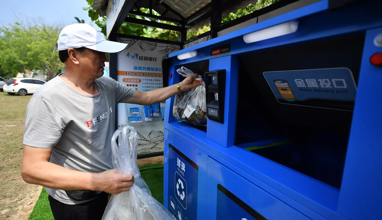 Turis memasukkan sampah ke bank sampah di Teluk Mulan, Kota Wenchang, Provinsi Hainan, China, 28 April 2020. Fasilitas bank sampah dibuat dengan wisatawan menukarkan sampah yang mereka kumpulkan di pantai dengan berbagai hadiah, seperti air kemasan, kelapa, serta makanan ringan. (Xinhua/Guo Cheng)
