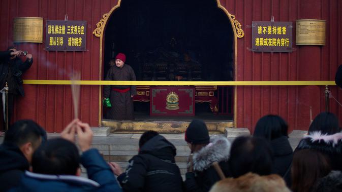 Seorang bhiksu memperhatikan orang berdoa di Kuil Lama di Beijing (5/2). Orang-orang China merayakan hari pertama Tahun Baru Imlek pada hari Selasa, Tahun Babi di zodiak Tiongkok dengan berdoa di kuil. (AP Photo/Mark Schiefelbein)