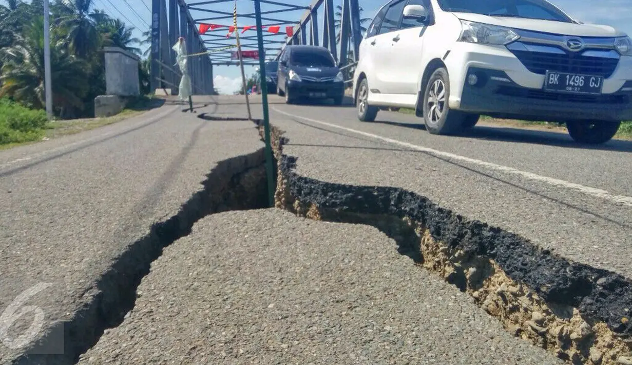 Kendaraan roda empat melintas pada jalan retak di Kabupaten Pidie Jaya, Aceh, Kamis (8/12). Gempa berkekuatan 6,5 SR pada Rabu pagi menyebabkan sejumlah ruas jalan retak dan mengalami kerusakan. (Liputan6.com/Angga Yuniar)