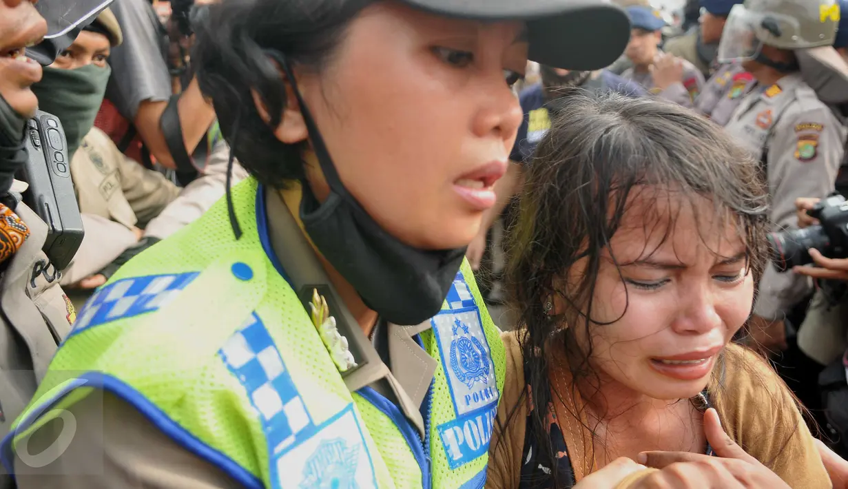 Seorang ibu menangis ketika diamankan petugas polwan dalam penggusuran di kawasan Pasar Ikan, Penjaringan, Jakarta, Senin (11/4). Warga yang didominasi perempuan itu ikut menolak penggusuran kawasan tersebut. (Liputan6.com/Gempur M Surya)