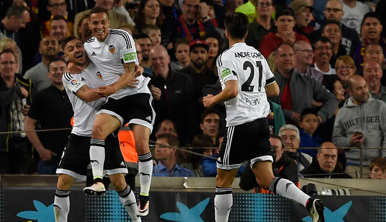 Gelandang Valencia, Guilherme Siqueira (kiri) melakukan selebrasi usai Ivan Rakitic memasukan bola kegawangnya sendiri di pertandingan liga Spanyol di Camp Nou stadium (18/4). Valencia menang atas Barcelona dengan skor 2-1. (AFP PHOTO/GENE Lluis)