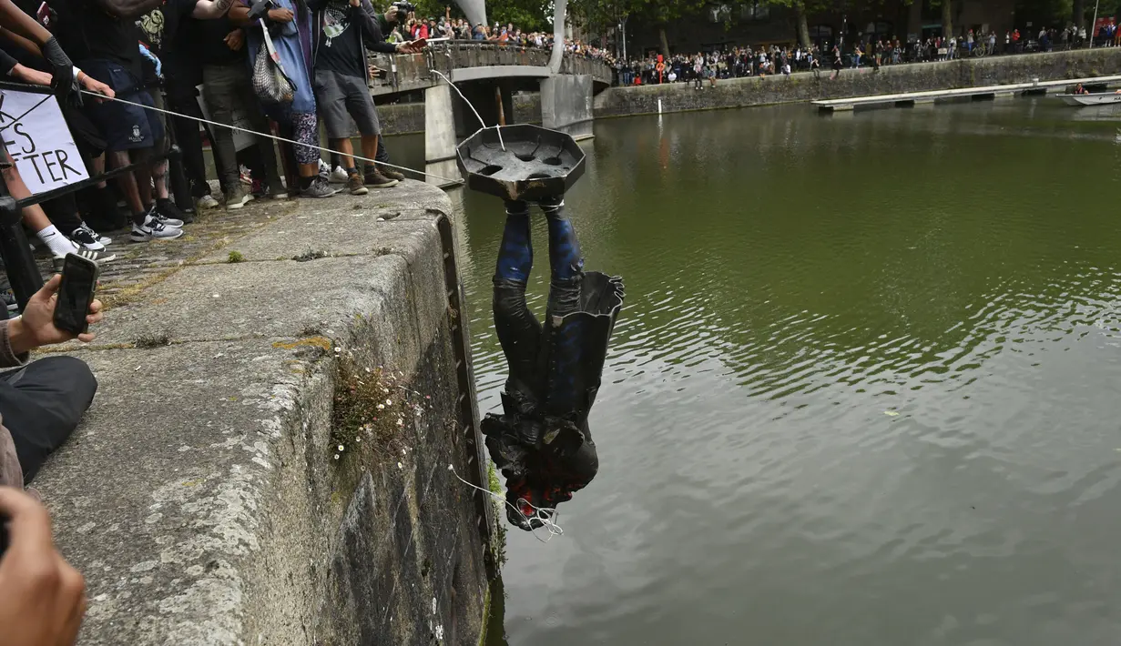 Demonstran melempar patung pedagang budak Edward Colston ke Pelabuhan Bristol saat protes Black Lives Matter di Bristol, Inggris, Minggu (7/6/2020). Aksi tersebut dilakukan sebagai bentuk protes atas kematian George Floyd saat ditangkap oleh polisi di Amerika Serikat. (Ben Birchall/PA via AP)