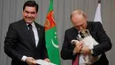 Presiden Rusia, Vladimir Putin (kanan) memncium anjing gembala Turkmen atau dikenal sebagai Alabai pemberian Presiden Turkmenistan Gurbanguly Berdimuhamedov saat pertemuan di Sochi, Rusia (11/10). (AFP Photo/Pool/Maxim Shemetov)