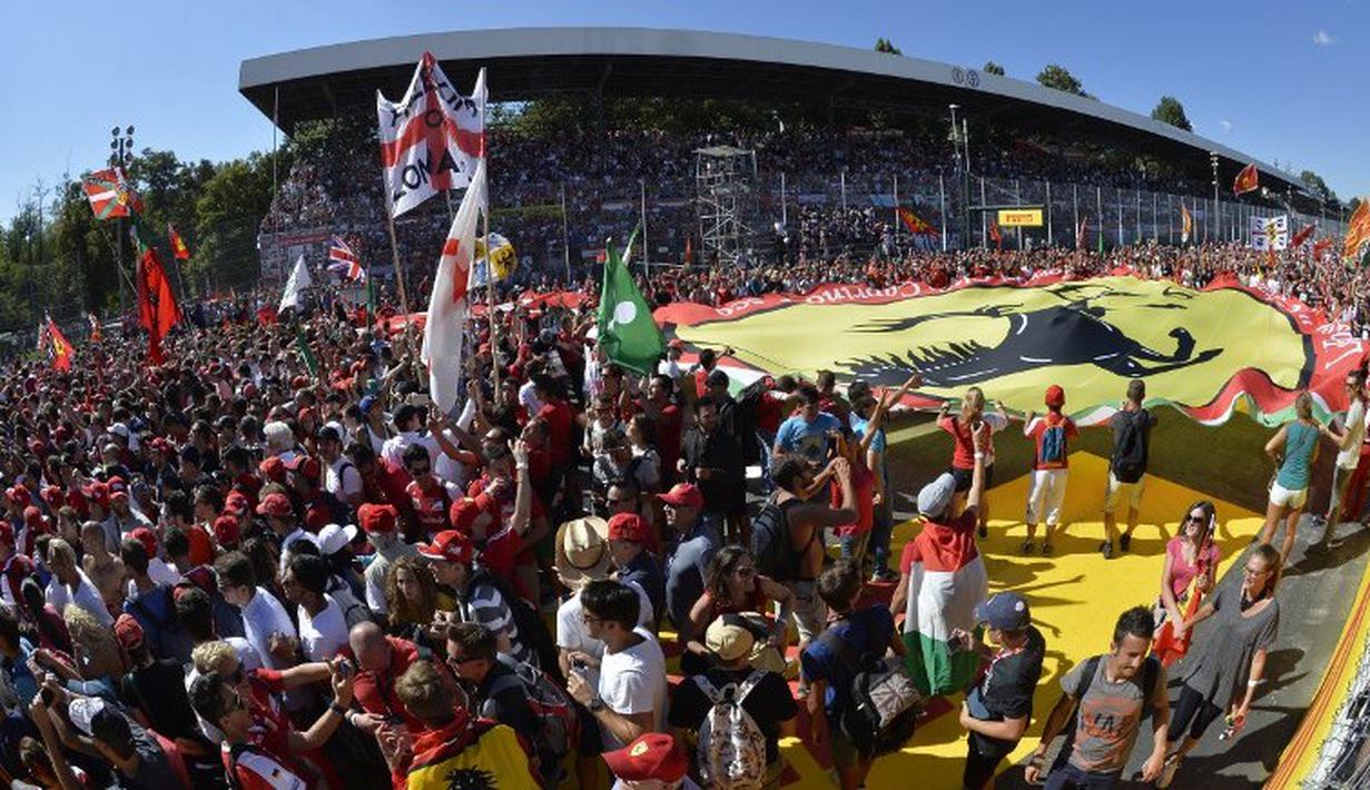 Suporter Ferrari memadati lintasan setelah pebalap Ferrari, Sebastian Vettel, berhasil meraih podium di Sirkuit Monza, Italia. Minggu (6/9/2015). (AFP Photo/Andreas Solaro)