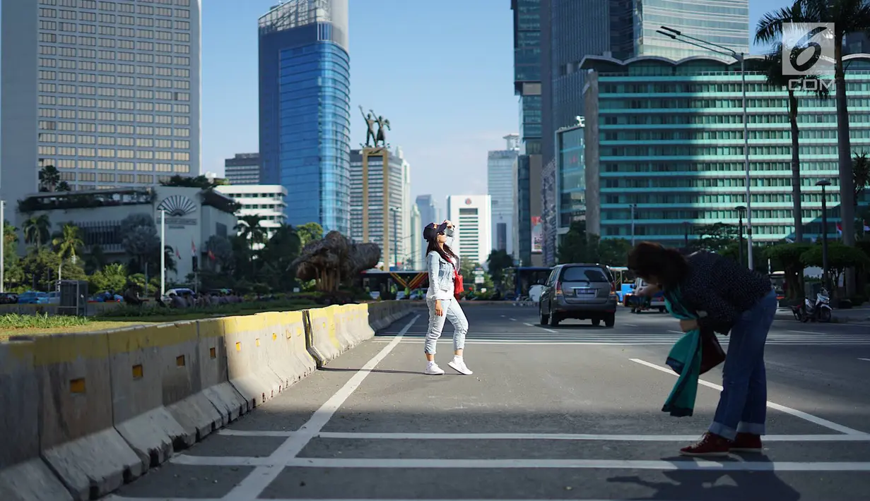 Seorang wanita berfoto dengan latar belakang Jalan MH Thamrin yang masih ditutup oleh aparat keamanan di Jakarta, Jumat (24/5/2019). Ditutupnya Jalan MH Thamrin terkait unjuk rasa menolak hasil Pemilu 2019 dimanfaatkan sebagian warga untuk berfoto. (Liputan6.com/Immanuel Antonius)